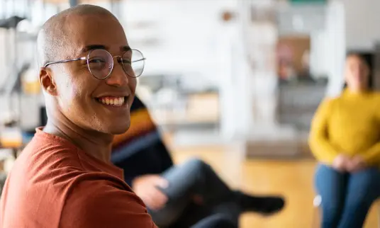 Man smiling in a room with other professionals